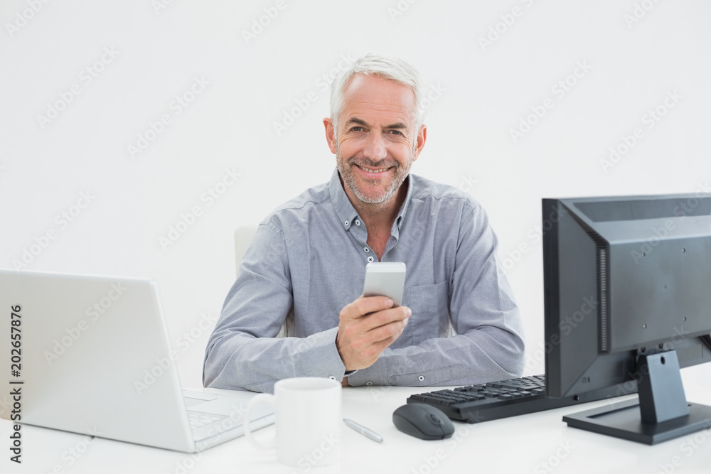 Businessman with cellphone, laptop and computer at desk Businessman with cellphone, laptop and computer at desk