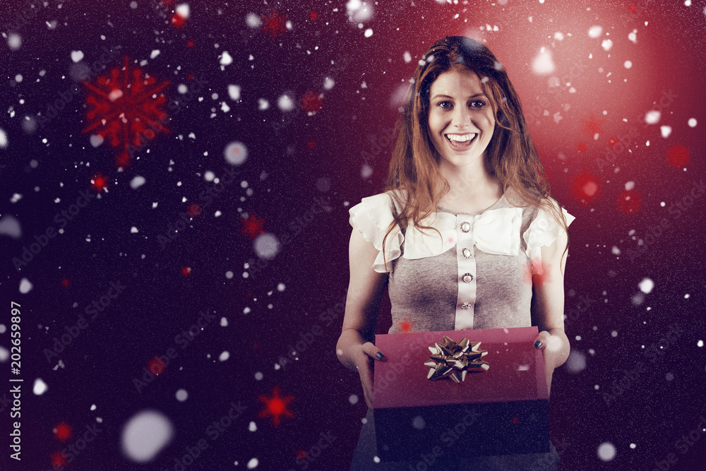 Pretty redhead offering a gift box against snow Pretty redhead offering a gift box against snow
