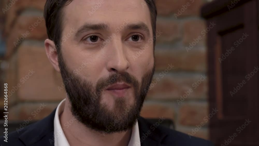 Closeup of a bearded man's face putting a piece of food in his mouth in a fine dining restaurant. Closeup of a bearded man's face putting a piece of food in his mouth in a fine dining restaurant.