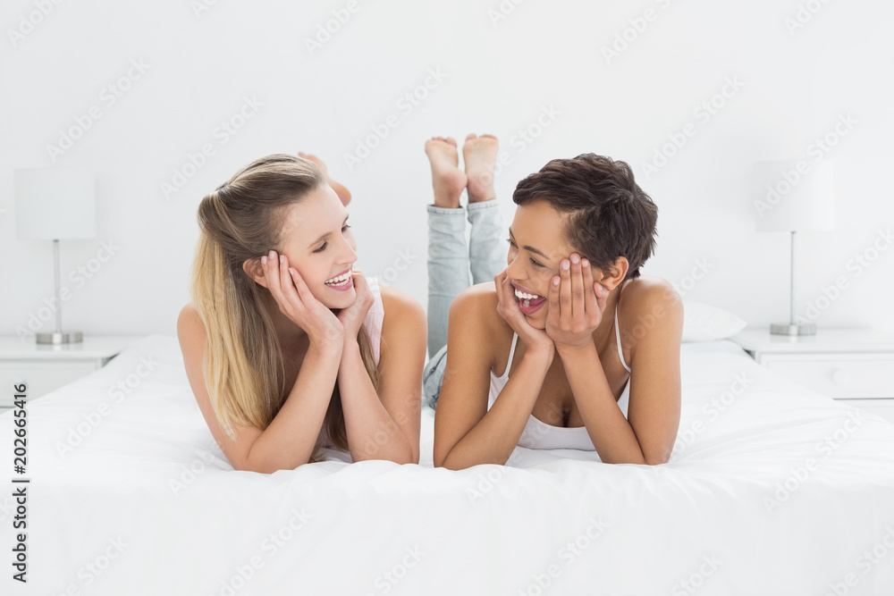 Cheerful young female friends lying in bed Cheerful young female friends lying in bed