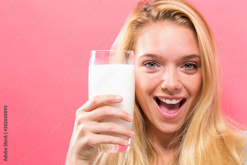 Happy young woman drinking a glass of milk on a solid background Happy young woman drinking a glass of milk on a solid background