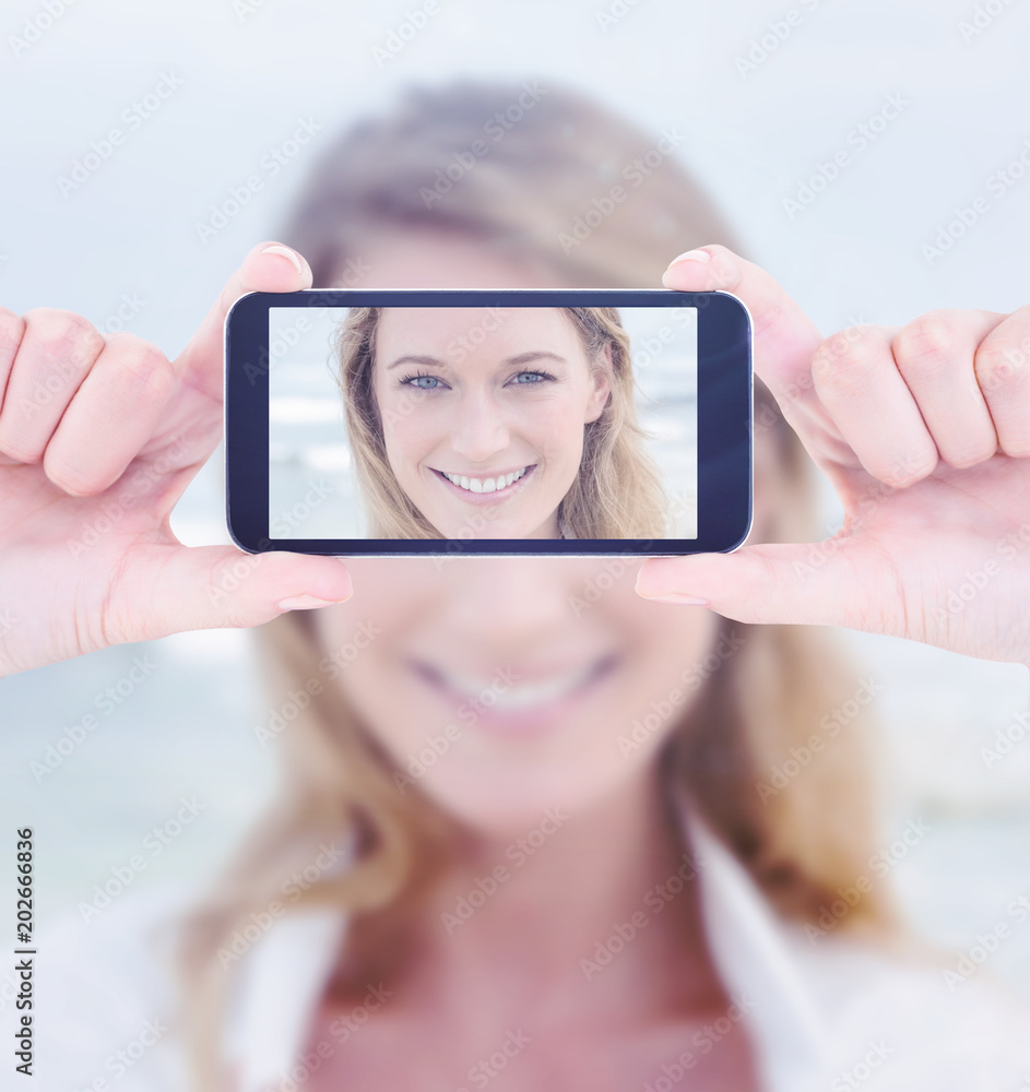 Hands holding smartphone against closeup portrait of a smiling casual woman at beach