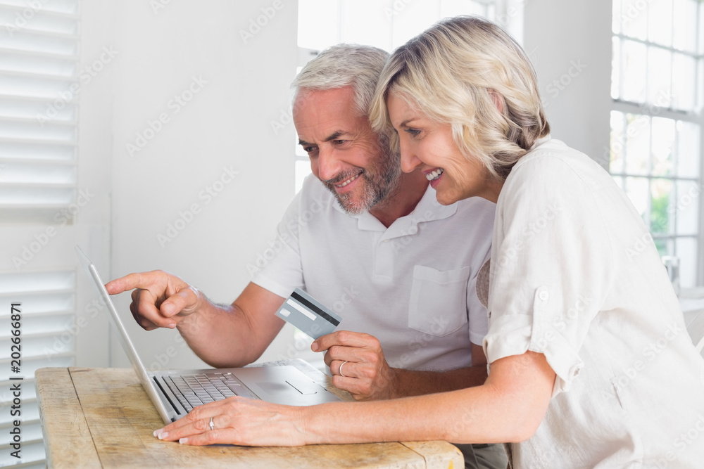 Happy mature couple doing online shopping at home Happy mature couple doing online shopping at home