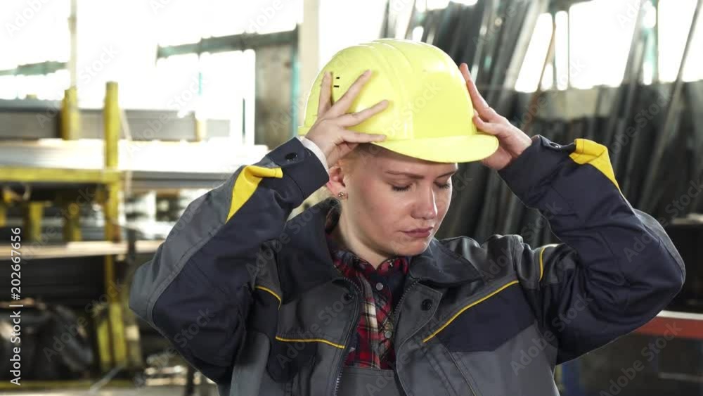Young beautiful female engineer looking tired and exhausted taking off her hardhat after work exhaling heavily. Tiredness, stress, overworking, industry, distribution concept. Young beautiful female engineer looking tired and exhausted taking off her hardhat after work exhaling heavily. Tiredness, stress, overworking, industry, distribution concept.