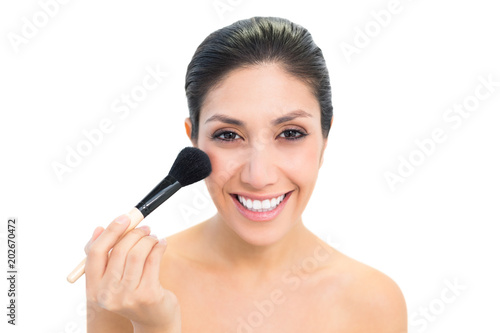 Brunette using a powder brush and smiling