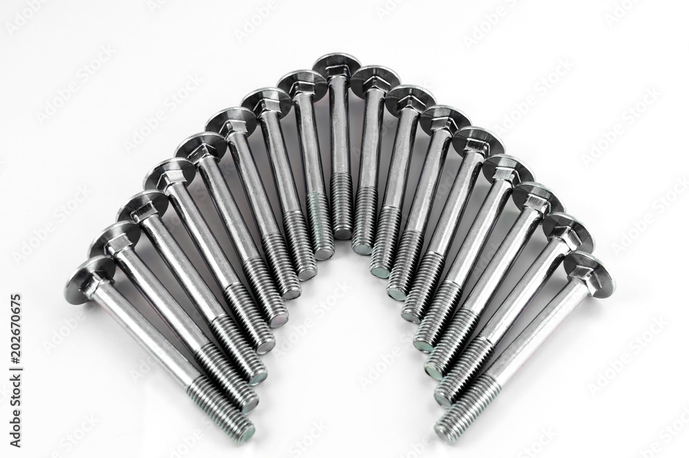 Metal bolts for fastening parts, stacked next to each other in the form of an arc on a white background. Metal bolts for fastening parts, stacked next to each other in the form of an arc on a white background.