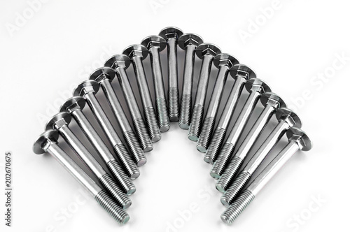 Metal bolts for fastening parts, stacked next to each other in the form of an arc on a white background.