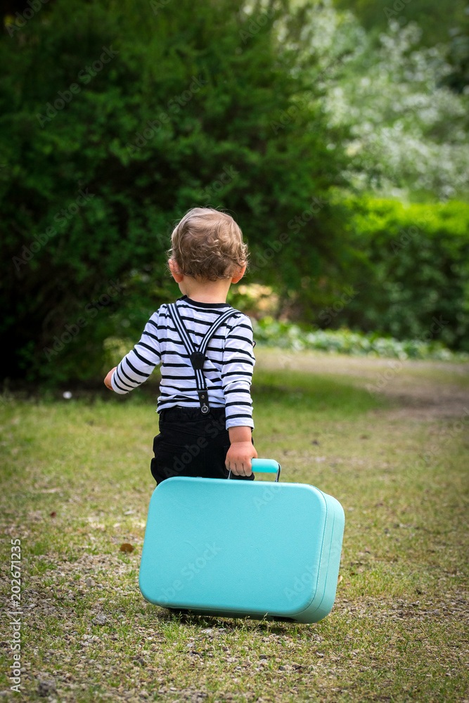 Φωτογραφία un petit garçon essaie d'emporter un valise trop lourde pour lui