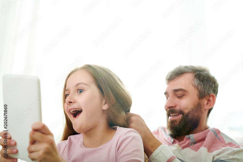 Funny little girl taking selfie with bearded dad on digital tablet while he combing her hair, close-up shot Funny little girl taking selfie with bearded dad on digital tablet while he combing her hair, close-up shot
