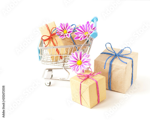 Creative concept of shopping trolley with wrapped gifts on light background.  photo