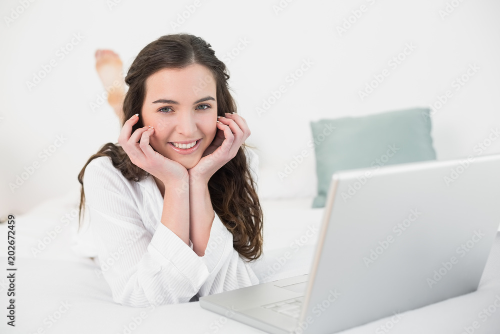 Relaxed smiling casual brunette with laptop in bed Relaxed smiling casual brunette with laptop in bed
