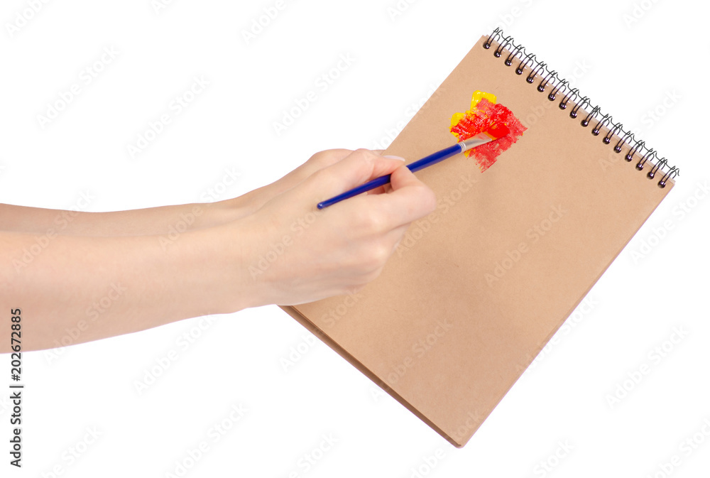 Notepad for drawing and brush with paint in hand