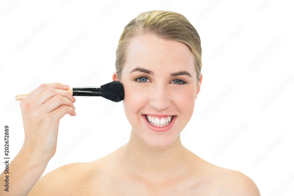 Smiling attractive blonde using blusher brush Smiling attractive blonde using blusher brush