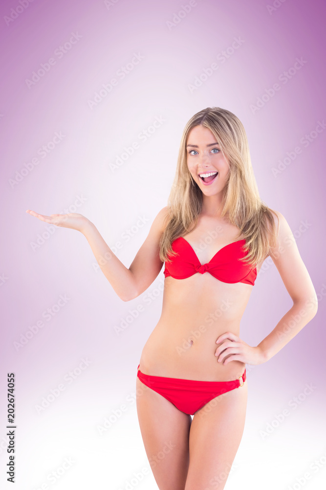 Fit blonde in red bikini showing scales on vignette background Fit blonde in red bikini showing scales on vignette background