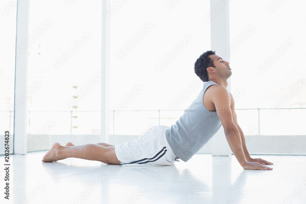Fit young man doing the cobra pose in fitness studio Fit young man doing the cobra pose in fitness studio