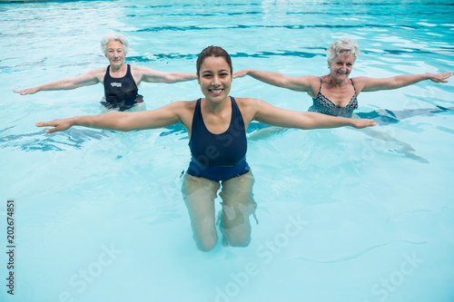 Female trainer with senior women exercising in swimming pool