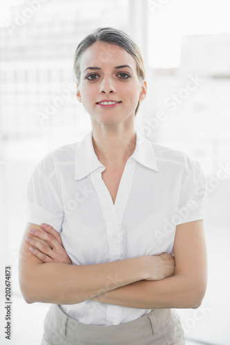 Attractive businesswoman posing with arms crossed looking at camera