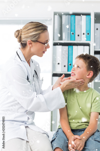 Composite image of Doctor examining thyroid gland of boy with snow falling