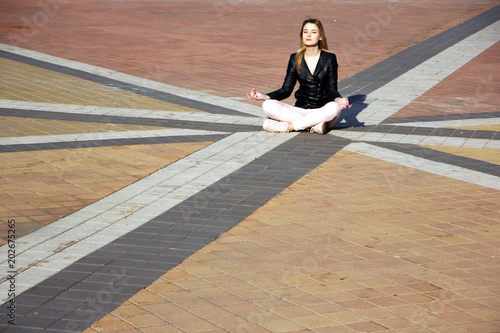 beautiful young woman meditating and exercise yoga in lotus position at street at beautiful sunny day