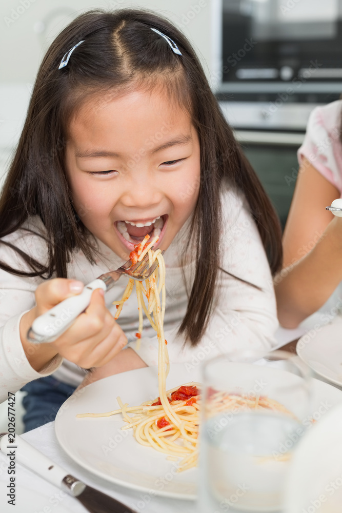 Happy young kid enjoying spaghetti lunch in kitchen Happy young kid enjoying spaghetti lunch in kitchen