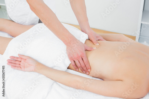 Mid section of a physiotherapist massaging womans back