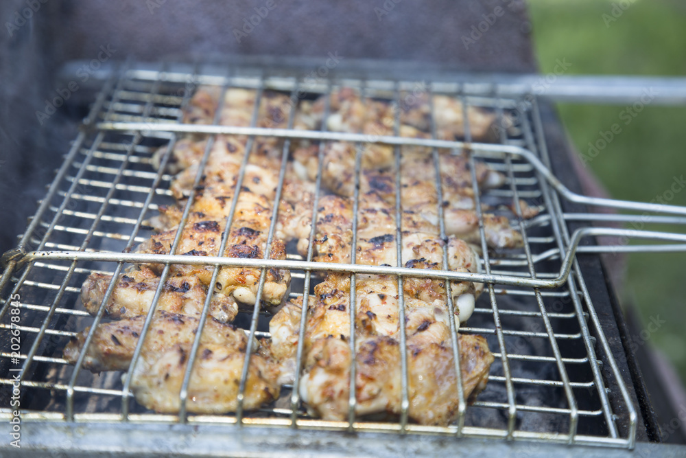 Chicken meat wings that turn over on a barbecue grill.Meat is fried in Mangal Barbecue grill. Chicken meat on the gril Chicken meat wings that turn over on a barbecue grill.Meat is fried in Mangal Barbecue grill. Chicken meat on the gril