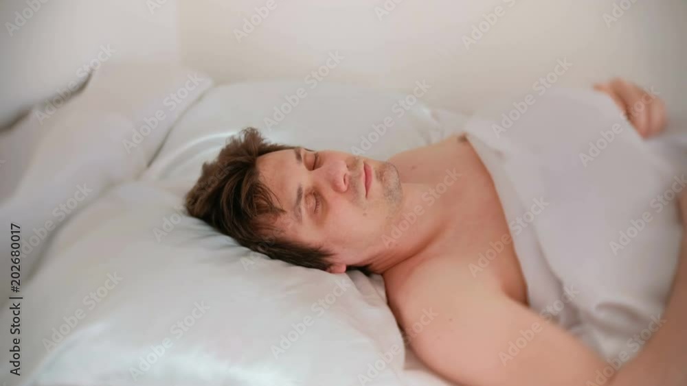 Young brunet handsome man falls asleep lying in bed. Young brunet handsome man falls asleep lying in bed.