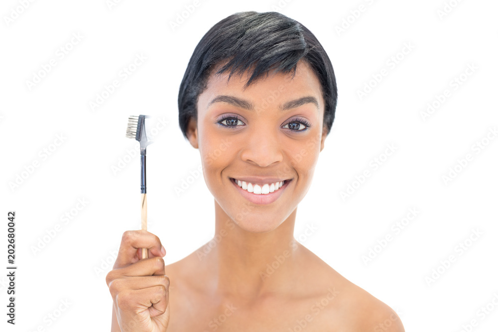 Happy black haired woman holding a brow brush Happy black haired woman holding a brow brush