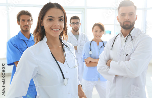 Attractive female doctor with medical stethoscope in front of medical group photo