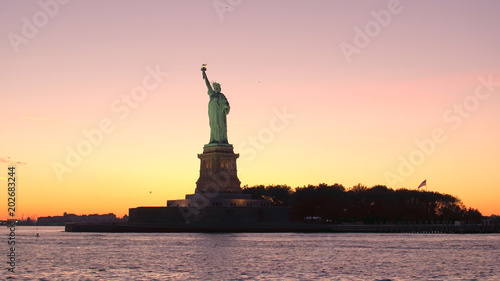 LOW ANGLE: Iconic Statue of Liberty against gorgeous fiery orange sunset sky © helivideo