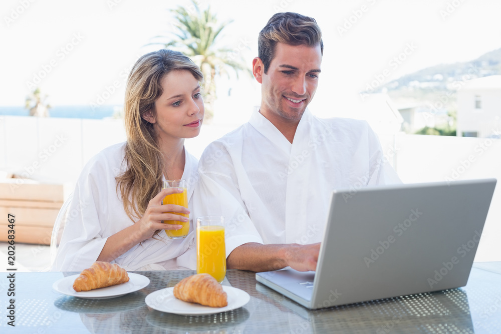 Couple using laptop on breakfast table Couple using laptop on breakfast table