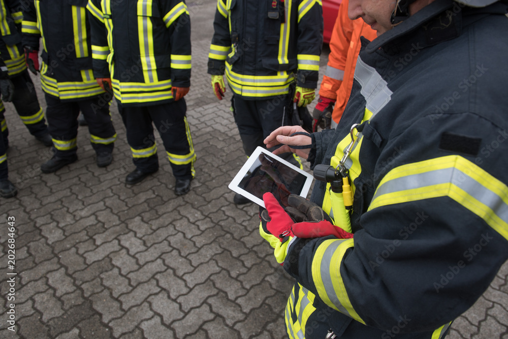Fototapeta premium Feuerwehrmann hält ein Tablet in der Hand