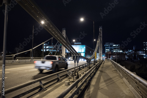 Modern steel bridge with traffic driving into the city center at night