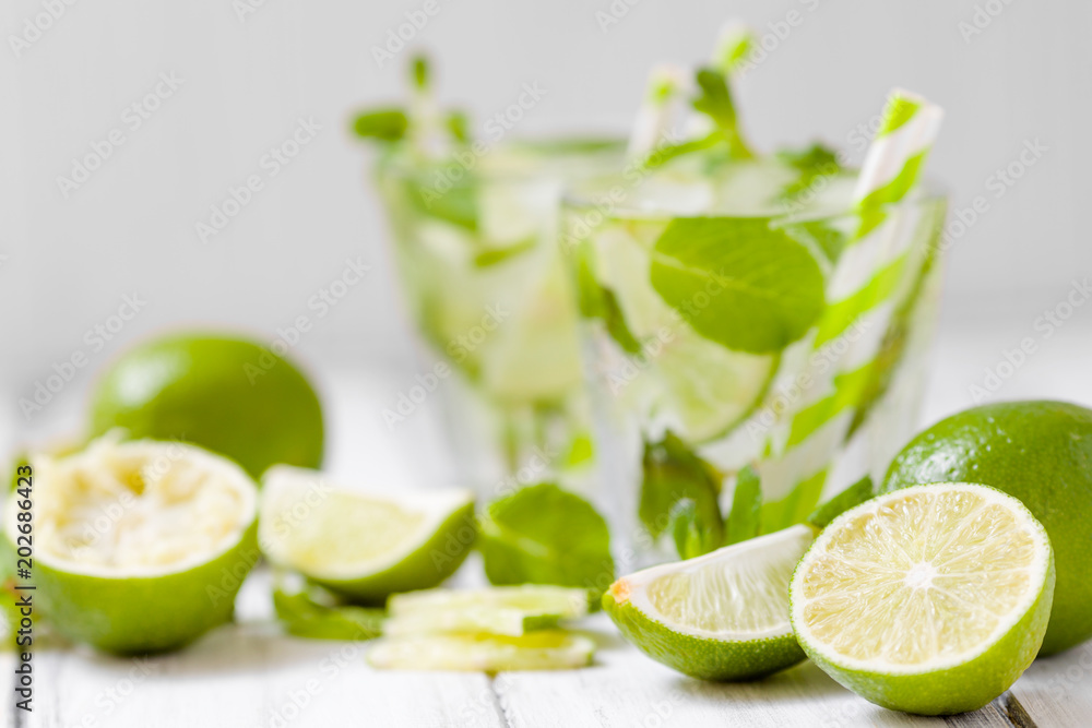 Summer refreshing cocktail mojito with lime and mint on white wooden vintage background. Summer refreshing cocktail mojito with lime and mint on white wooden vintage background.