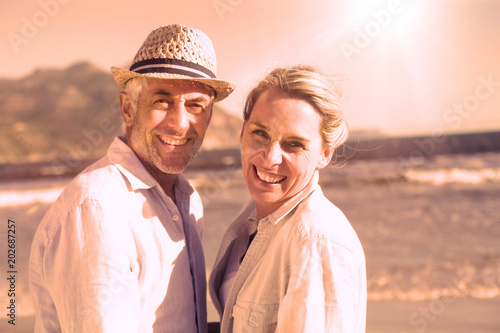 Happy couple standing on the beach together on a sunny day © vectorfusionart