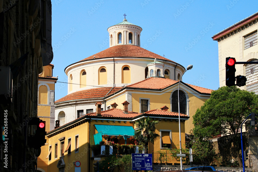 Circular shape sunlit landmark Baroque cathedral of St. Vitus patron saint of the city against the blue sky in a sunny summer day, view from streets of downtown Rijeka port town Croatia Balkans Europe