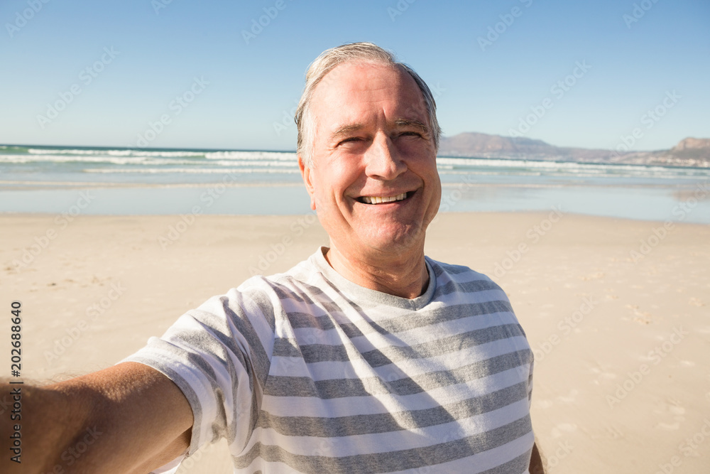 Portrait of happy senior man standing at beach