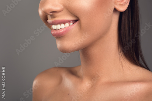 Close up of laughing woman with snow white smile and naked shoulders. Isolated on background