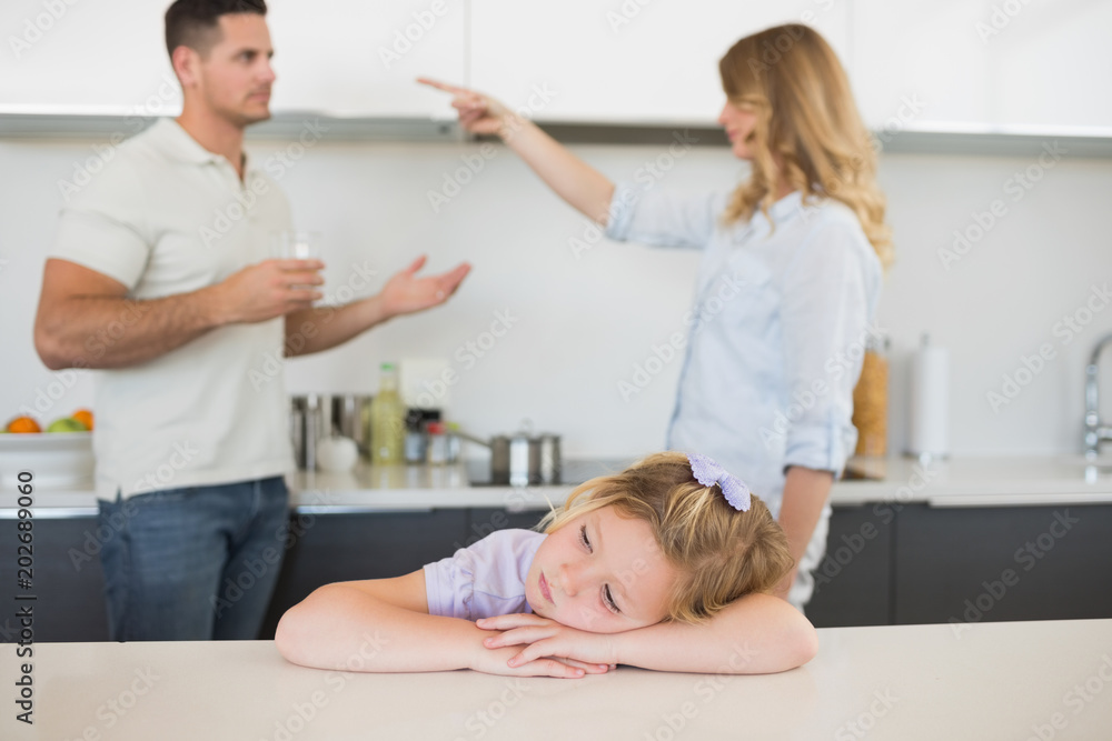 Girl at table with parents arguing in background Girl at table with parents arguing in background