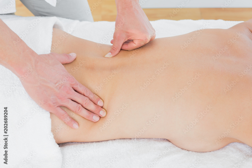 Mid section of a physiotherapist massaging womans back Mid section of a physiotherapist massaging womans back