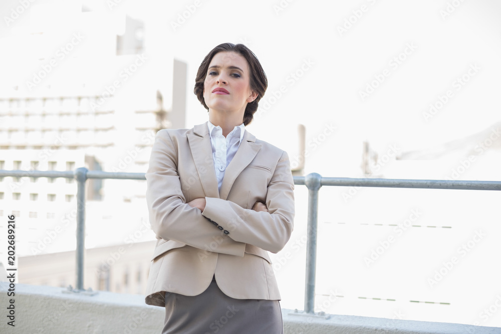 Attractive stylish brown haired businesswoman standing with arms folded Attractive stylish brown haired businesswoman standing with arms folded