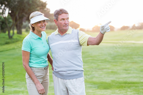 Golfing couple smiling at camera on the putting green 