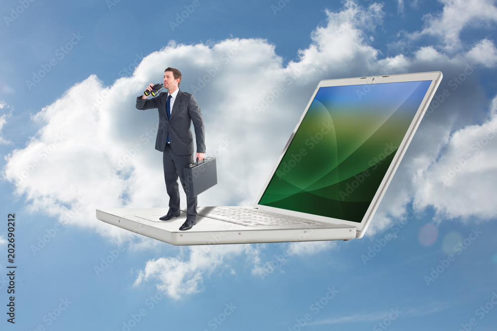 Fotografie Businessman looking through binoculars against cloudy sky