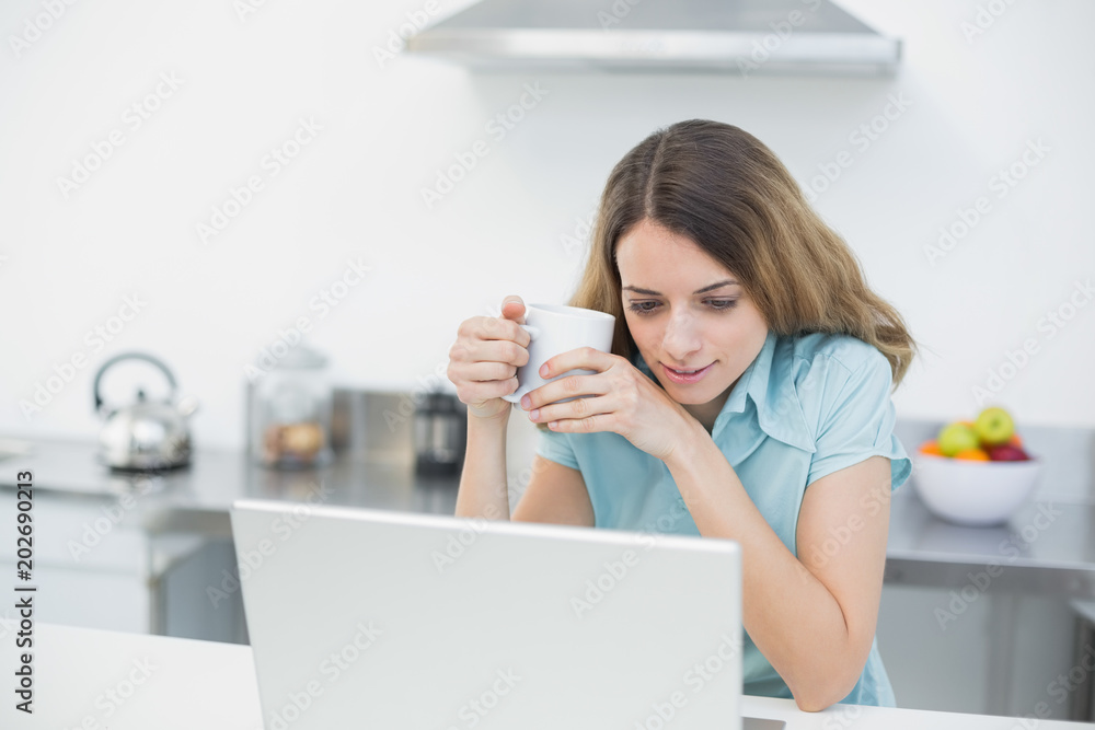 Cute calm woman working with her notebook holding a cup Cute calm woman working with her notebook holding a cup