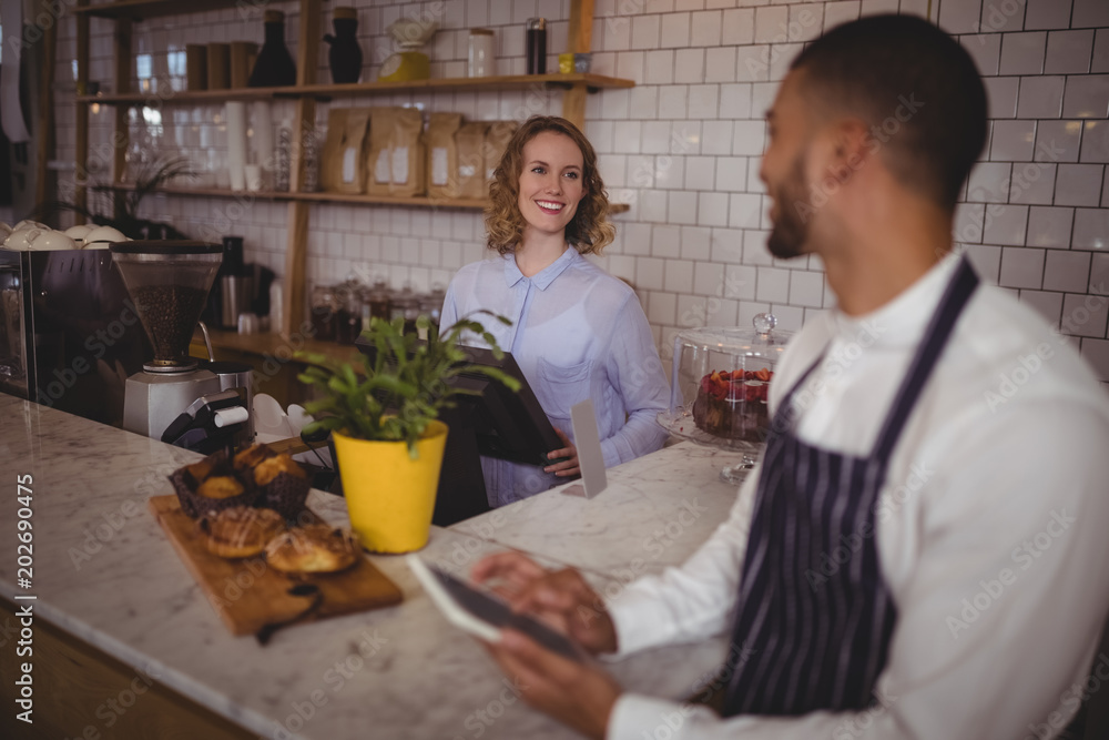 Smiling young waiter and waitress standing at counter Smiling young waiter and waitress standing at counter