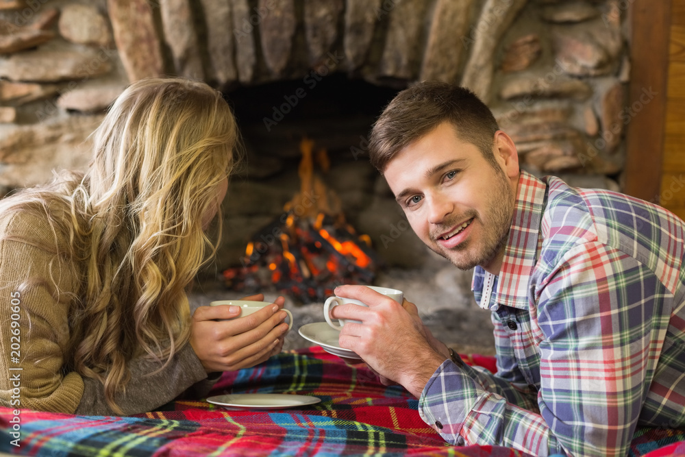 Couple with tea cups in front of lit fireplace Couple with tea cups in front of lit fireplace