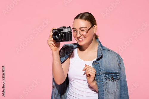 Portrait of joyful young woman is closing one eye while looking into camera lens with joy. Isolated