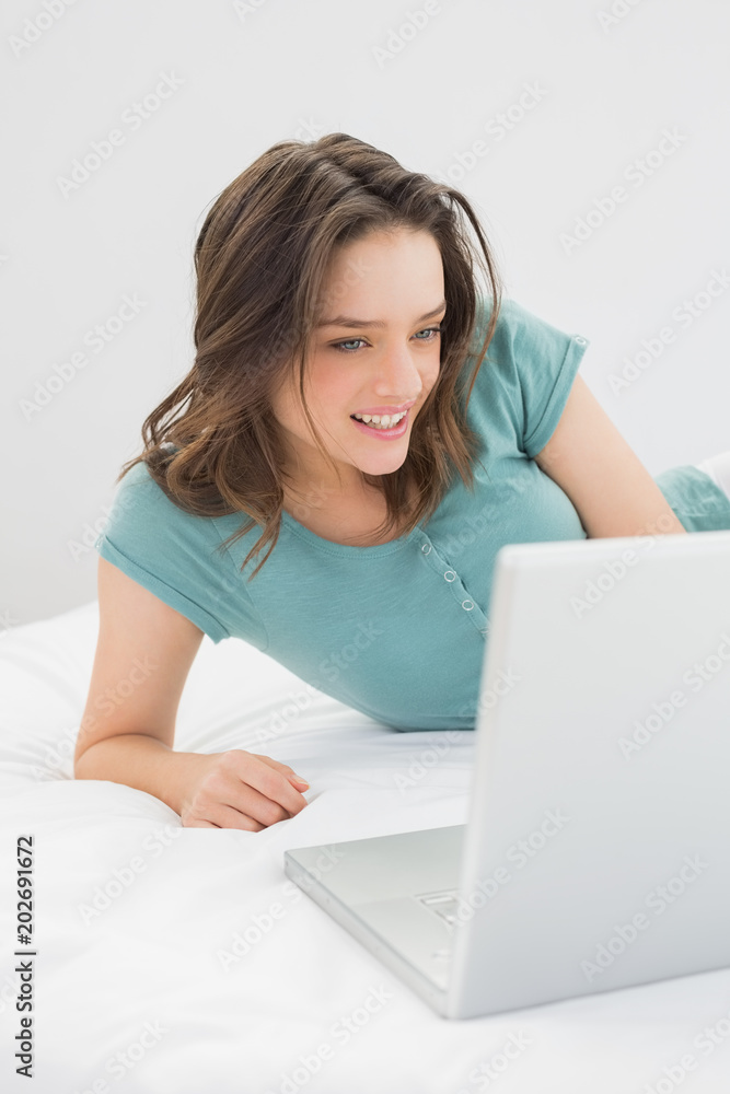 Smiling casual woman using laptop in bed Smiling casual woman using laptop in bed