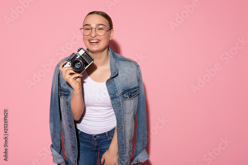 Portrait of joyful young woman is photographing by camera and laughing. Copy space
