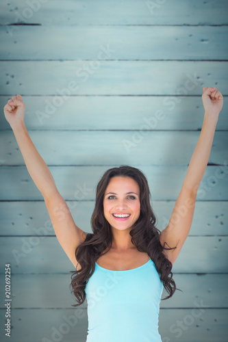 Casual brunette cheering at camera against wooden planks